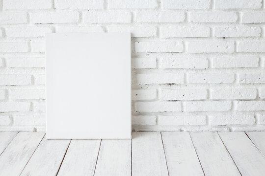 Empty white canvas frame on a wooden table
