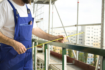 Ręce pracownika budowlanego mierzą odległość miarką. Praca na budowie.