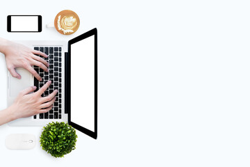 Man is typing on laptop kayboard over white table. Blank screens of laptop and smartphone canbe...