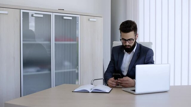Businessman typing on his phone while sitting in office