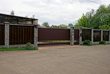 Fototapeta na wymiar коричневые ворота и забор пере асфальтированной дорогой