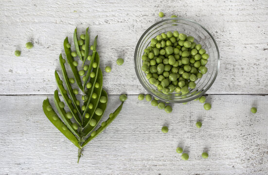 Green peas, freshly picked, arranged on wooden background. Top view