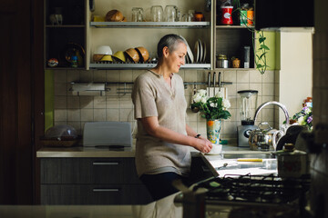 Portrait of middle aged woman woman holds a cup with coffee or tea against kitchen background.