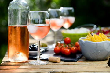 holiday summer brunch party table outdoor in a house backyard with appetizer, glass of rosé wine, fresh drink and organic vegetables