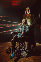 Fototapeta na wymiar Maniac and his tied victim in the wheelchair on the dark background.