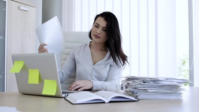 Attractive woman in very hot office trying to cool down with paper