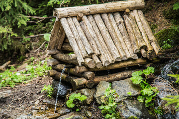 Natural source of spring water in forest flowing from a wooden well