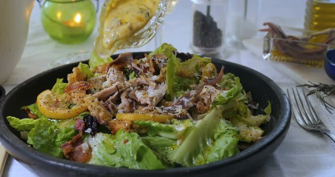 Pouring dressing sauce over a delicious Caesar's salad