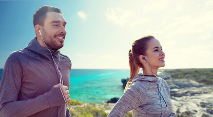happy couple with earphones running in city