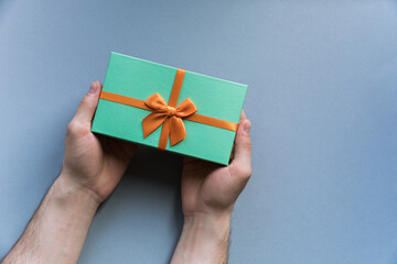 Flatlay holidays mint giftbox present in man hands on the pastel blue background for father's day, christmas, birthday party
