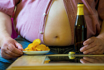 ein dicker Mann ernährt sich unvernünftig von Bier und Kartoffelchips - obrazy, fototapety, plakaty