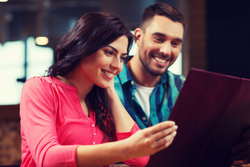 smiling couple with menus at restaurant