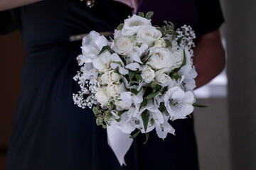 Bouquet di orchidee e rose bianche tenuto da una mano