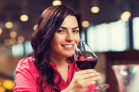 smiling woman drinking red wine at restaurant