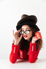 Concentrated serious young caucasian lady wearing hats by sale.