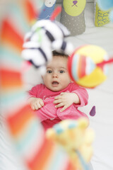 playful baby boy laughing and looking up to his toys in his crib