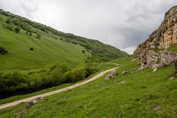 Горная дорога в живописном ущелье между зелеными склонами, горный пейзаж, путешествие по Северному Кавказу