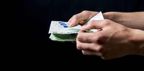 isolated 100 euro cash holding on a black background.