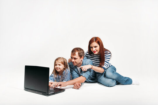Happy family Father, mother and child lying on the floor with laptop on white background isolated