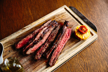 Juicy grilled steak on a wooden Board, with fragrant oil and sauce. The view from the top.