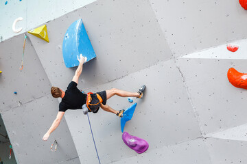 Male Climber sportsman hanging on artificial Climbing Wall, Competition in difficulty contest