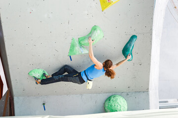 Woman making Free bouldering competition session at Indoor Rock Climbing wall © EdNurg