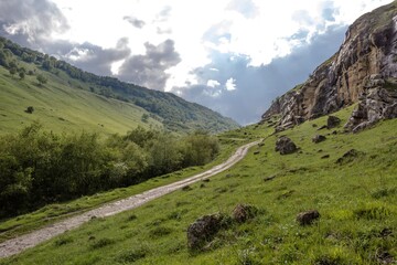 Горная дорога в живописном ущелье между зелеными склонами, горный пейзаж, путешествие по Северному Кавказу