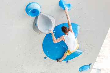 Sports Man professional climber on artificial climbing wall in bouldering gym