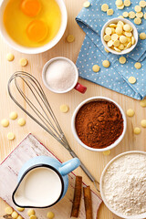 Baking utensils and ingredients. Egg yolk, cocoa, milk, flour, whisker, spoons, cinnamon, bowl, sweet decoration elements. Top view. Flat lay