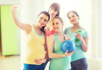pregnant women taking selfie by smartphone in gym