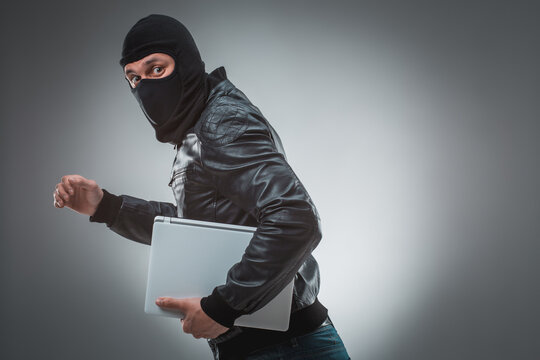 Thief stealing a laptop computer. Isolated on gray background