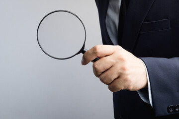 Business man hand holding magnifier for inspection