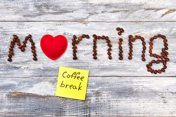 Note coffee break, wooden table. Red heart, word morning.
