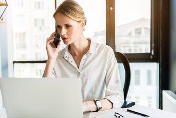 Serious woman is communicating by mobile phone with frustrate