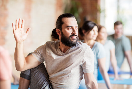 man with group of people doing yoga at studio