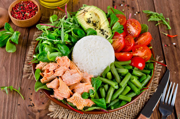 Healthy salad bowl with salmon, rice, tomatoes, avocado, mix salad, green beans