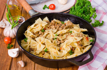 Pasta farfalle with fried meat, mushrooms and vegetables