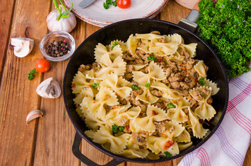 Pasta farfalle with fried meat, mushrooms and vegetables