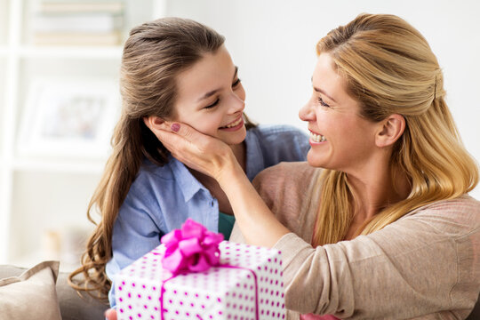 girl giving birthday present to mother at home