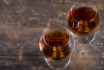 Wine glasses with brandy on vintage wooden background. Top view. Copy space for text. 