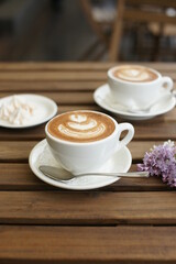 Two cups of cappuccino on a wooden table.