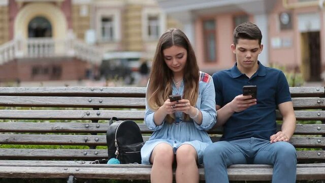 Couple in disinterest moment with phones outdoors