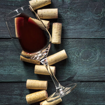 Glass of red wine and corks on dark background