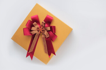 Top view of yellow gift box with red ribbon on white background, holiday and event concept