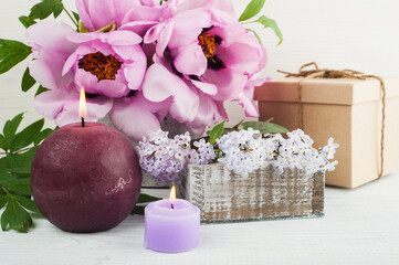 Lit candles, peonies and lilac flowers