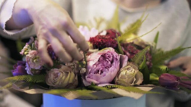 Close up of an unrecognisable shop assistant s hands putting roses in a box for delivery. Handheld real time close up shot