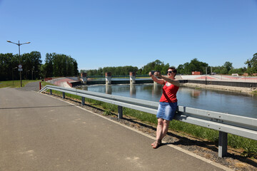Kobieta robi sobie zdjęcie smartfonem nad rzeką.