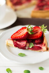 Fresh homemade tart with ricotta cheese and strawberries on white wooden table. Selective focus