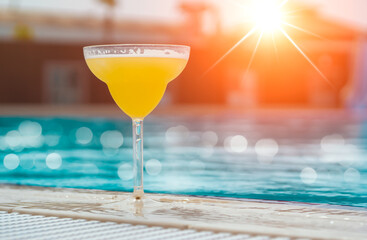 glass of pina colda next to swimming pool