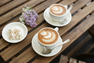 Two cups of cappuccino on a wooden table.